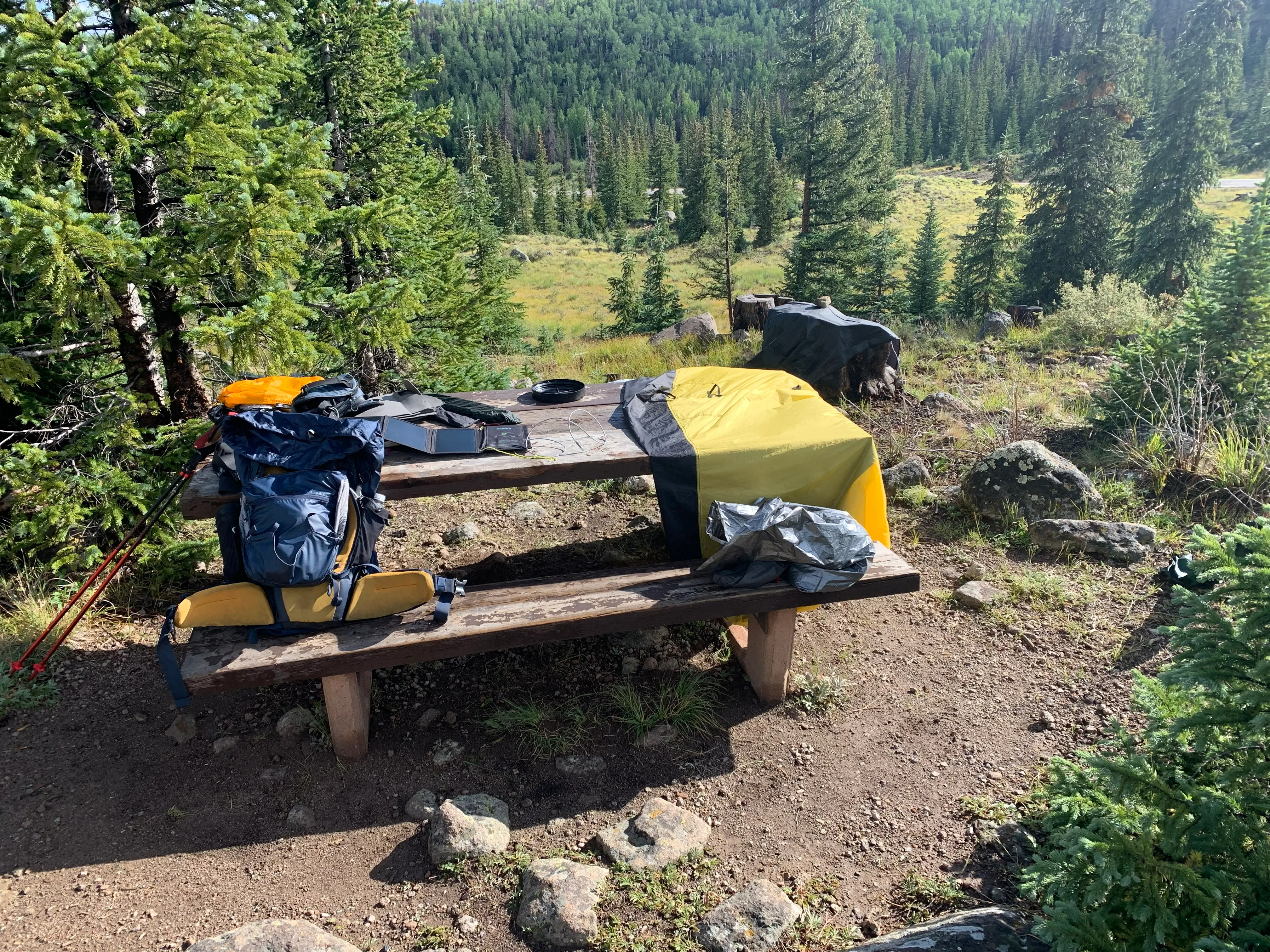 Picknick-Bank und Tisch im Wald mit Rucksack und Ausrüstung